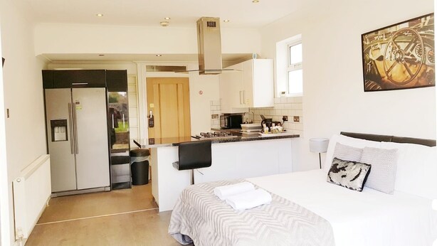 A modern hotel room with a bed, a small kitchenette, and a bathroom. - The 329 (Enfield)