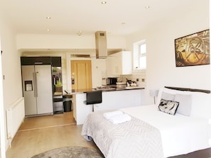 Una habitación de hotel moderna con cama, kitchenette pequeña y baño.