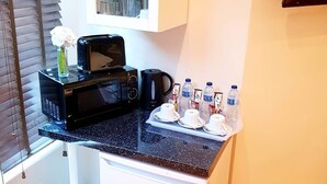 A kitchenette with a microwave, coffee maker, and water bottles on the counter. - The 329 (Enfield)