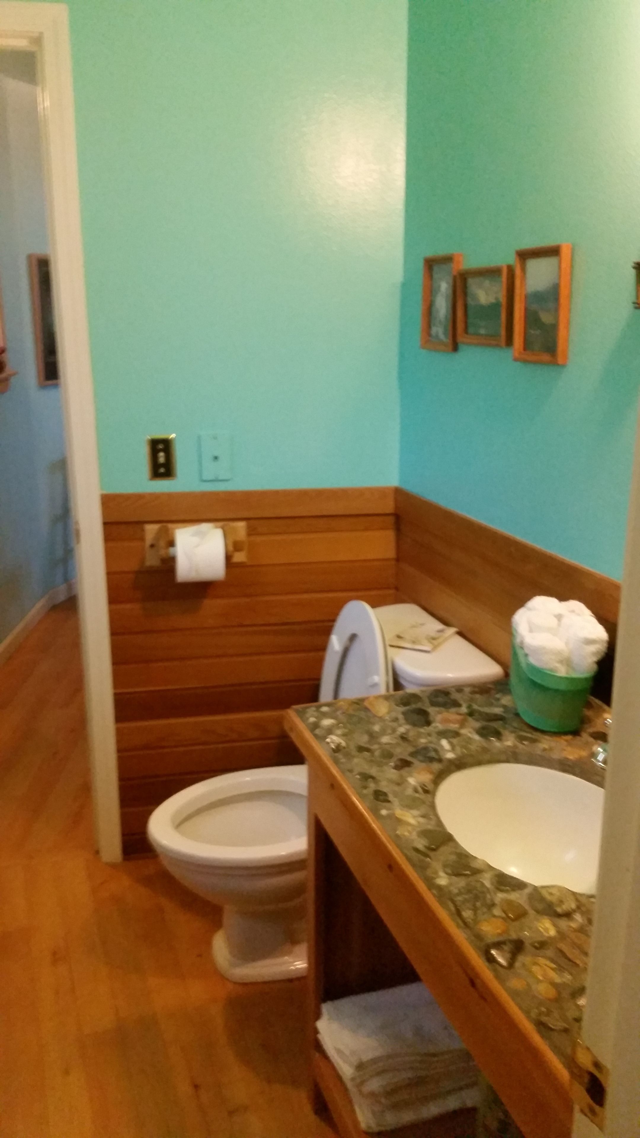 A bathroom with a wooden vanity, a white sink, and a toilet.