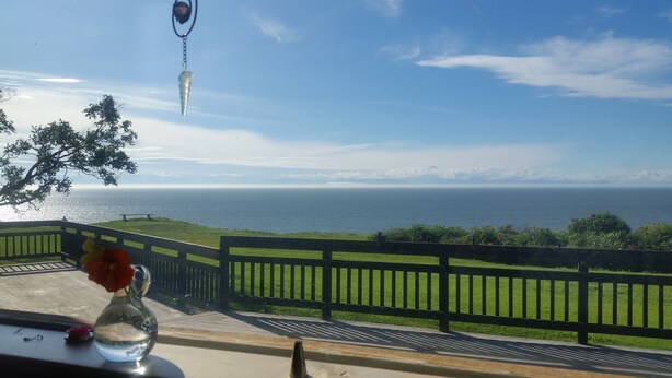 Vista del océano desde un balcón con un florero de vidrio y un llavero.