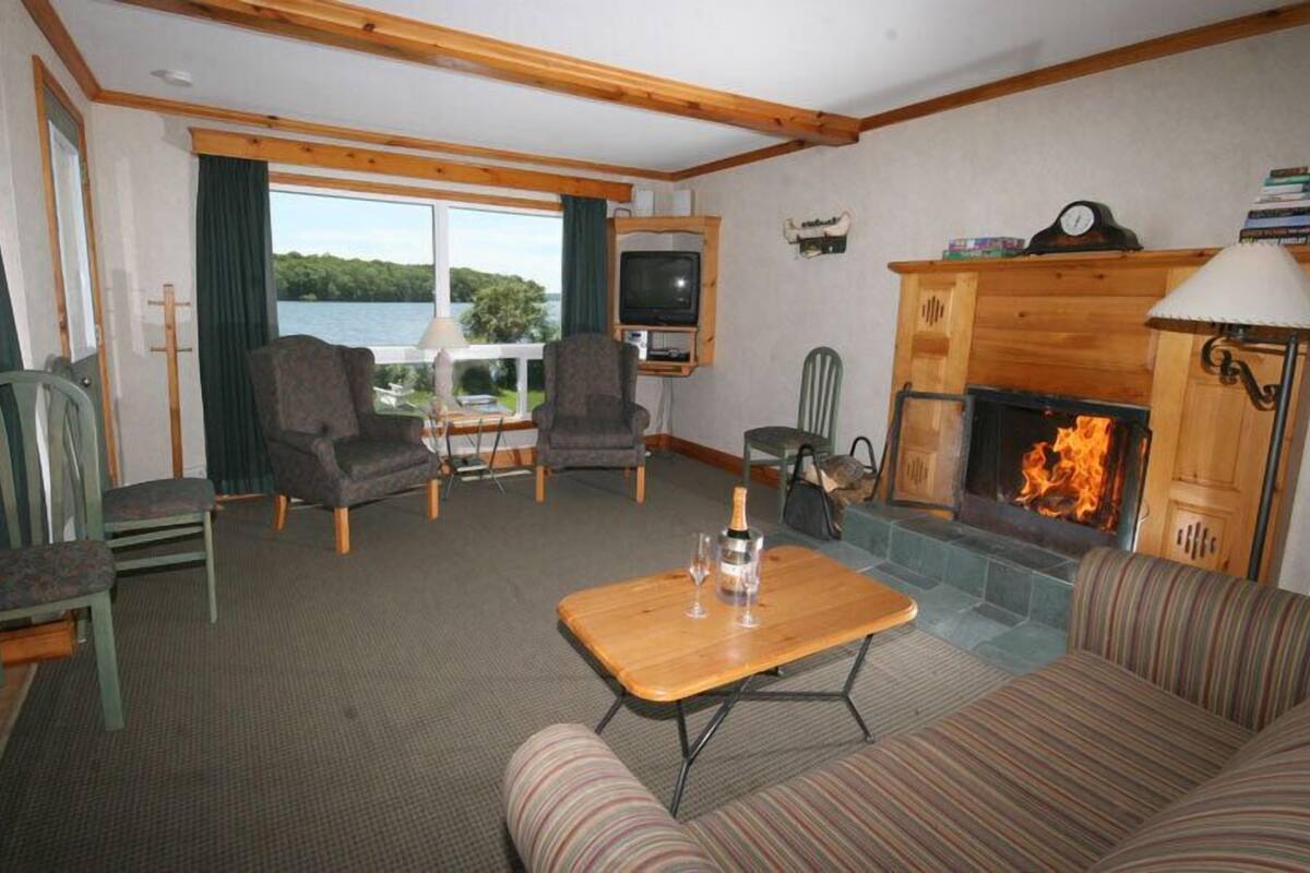 Una sala de estar acogedora con chimenea, televisor y vista al lago.