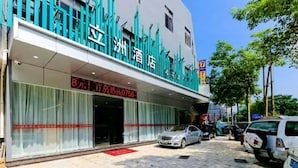 A hotel with a modern facade, a visible entrance, and a parking area with several cars. - Jinlizhou Hotel (Zhuhai)