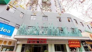 A hotel with a modern facade, multiple balconies, and signage indicating amenities such as a restaurant and a business center. - Jinlizhou Hotel (Zhuhai)