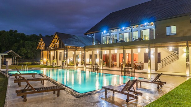 Un hotel moderno con piscina, mobiliario de exterior y un patio cubierto.