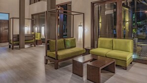 Un área de estar moderna con un sofá para cuatro personas, una mesita de centro y una silla con estructura de madera.