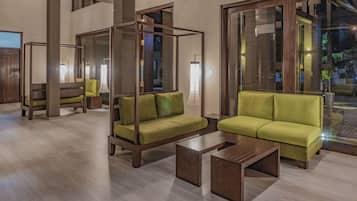 Relax in a spacious, open-plan area with a high ceiling and large windows, featuring a comfortable sofa and four-poster bed.
