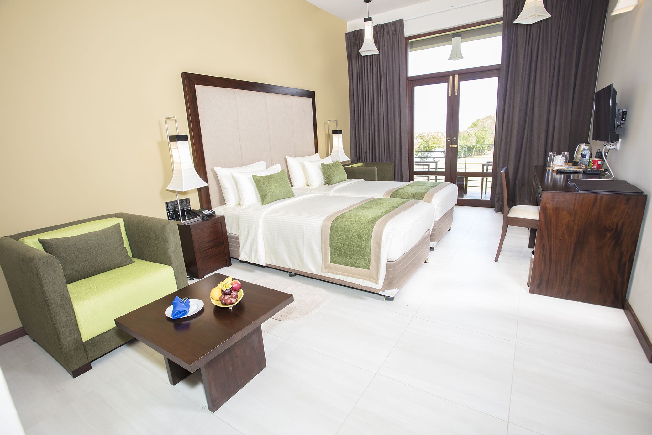 A hotel room with a large bed, a sofa, a desk, and a dining table.