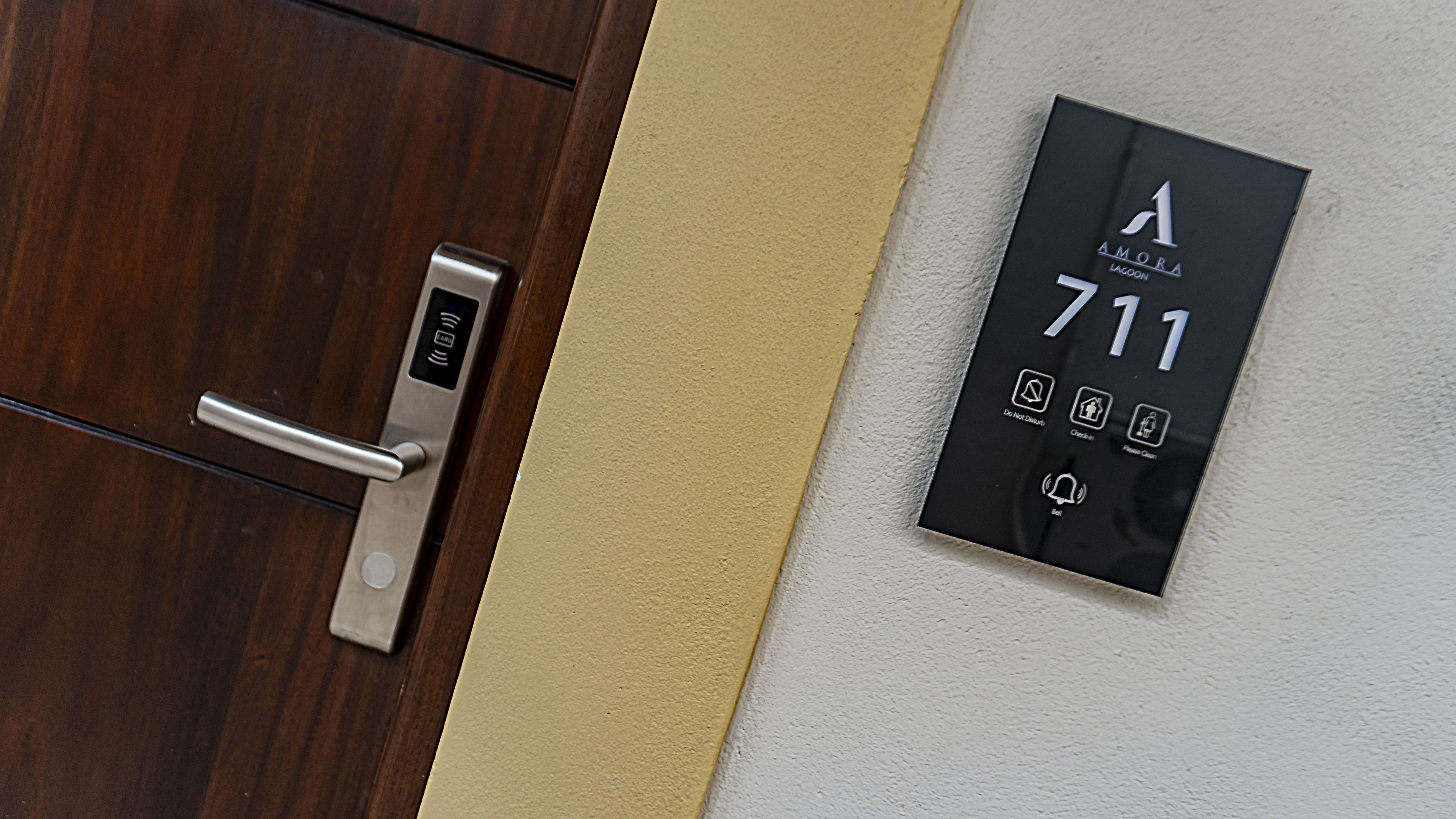 A modern hotel room door with a digital keypad and a wall-mounted number plate displaying room number 711.
