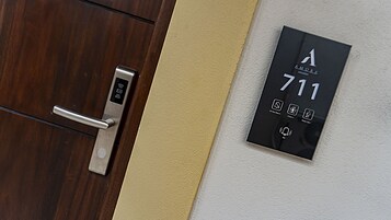A modern hotel room door with a digital keypad and a wall-mounted number plate displaying room number 711.