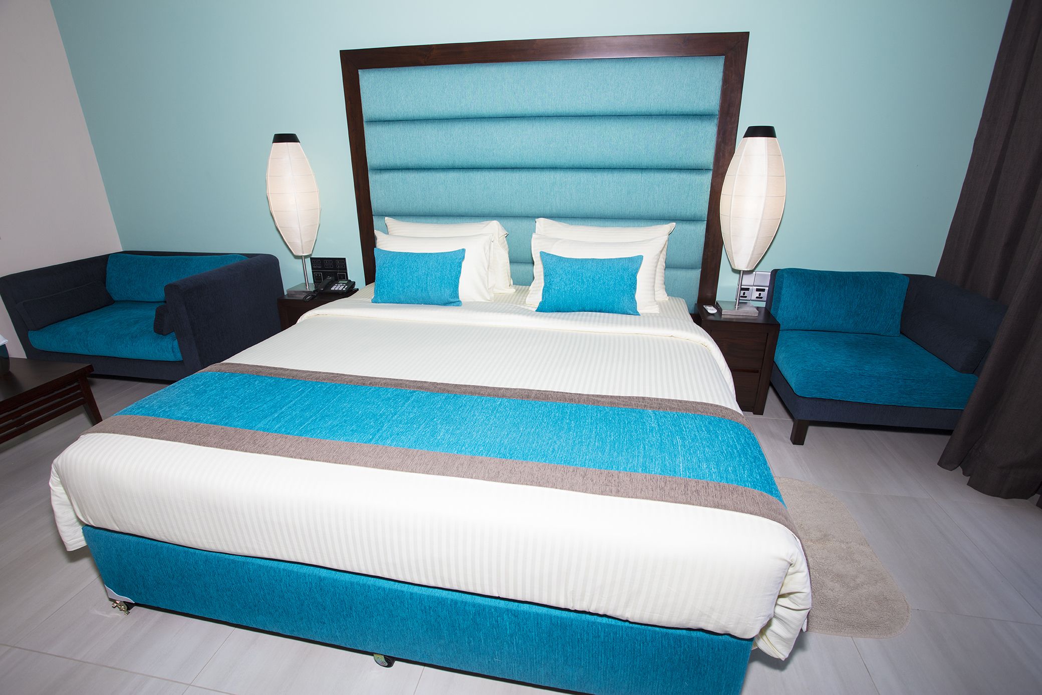 A hotel room with a large bed, two bedside tables, and two chairs.