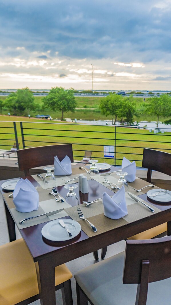 Una mesa lista para comer con vista a un campo cubierto de hierba y árboles al fondo.