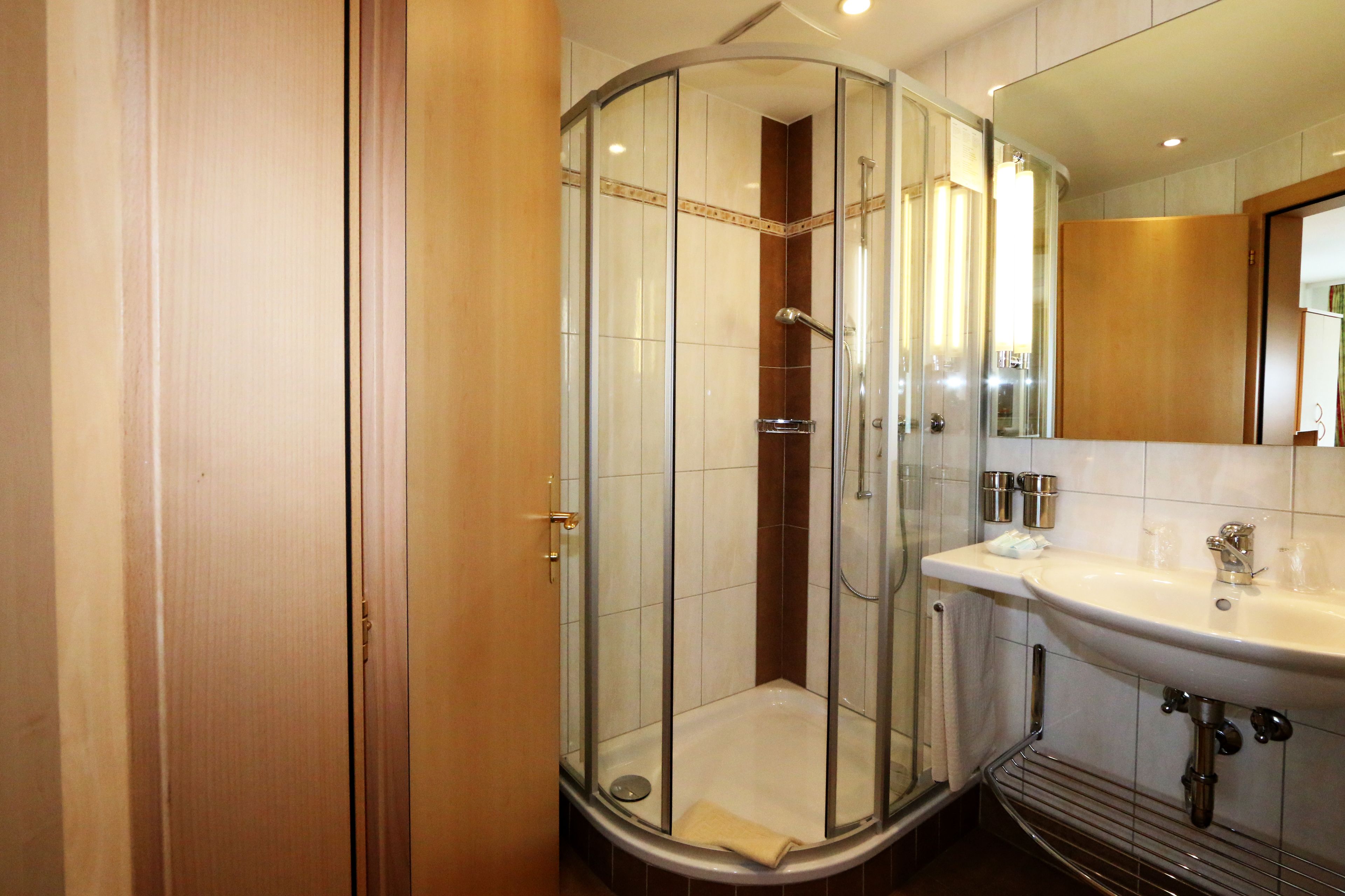 A modern bathroom with a glass-enclosed shower, a sink with a mirror, and a towel rack.
