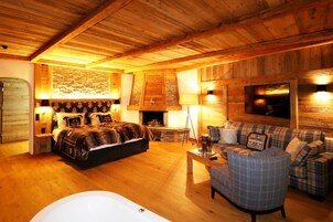 Un acogedor interior de cabaña de madera con una cama grande, un sofá, una chimenea y un televisor.
