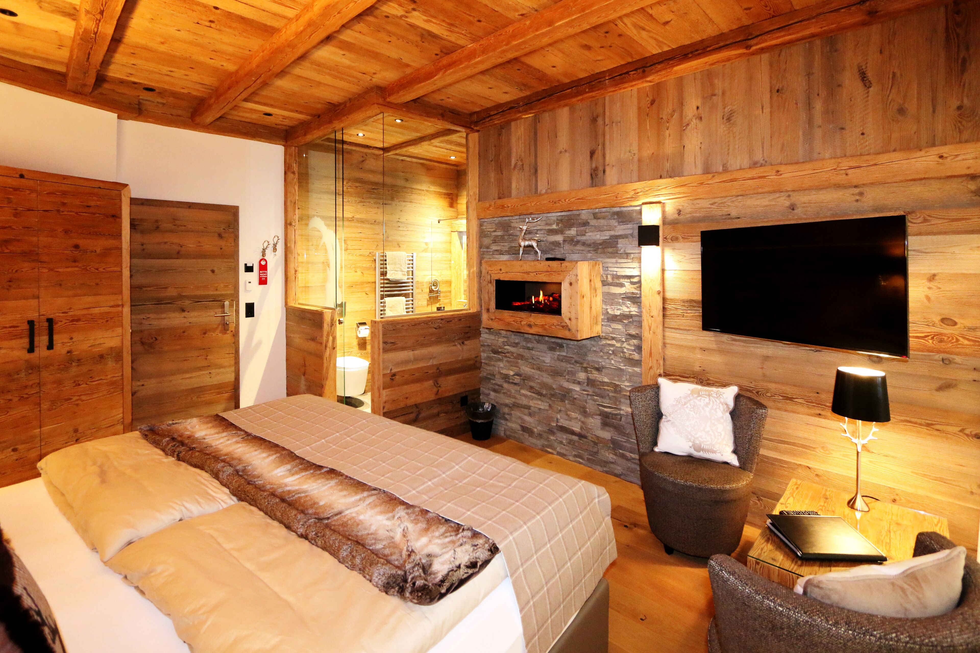 Un intérieur en bois comprenant un lit, un coin salon et une cheminée.