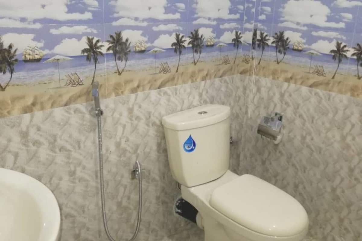 Une salle de bain avec un décor mural sur le thème de la plage, des toilettes et un lavabo.