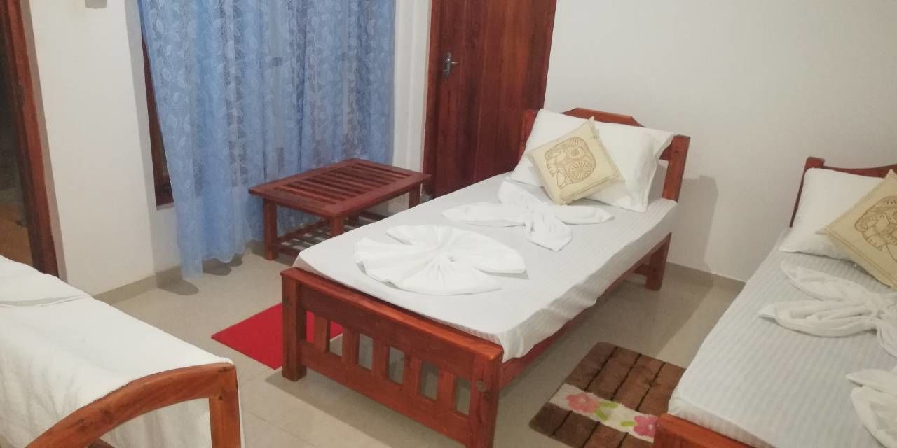 A room with two single beds, a wooden bench, and a small table.