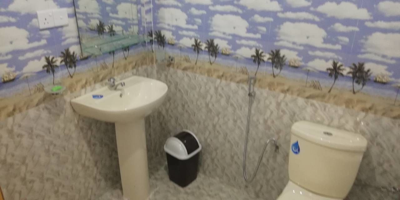 A bathroom with a beach-themed wall mural, a sink, and a toilet.