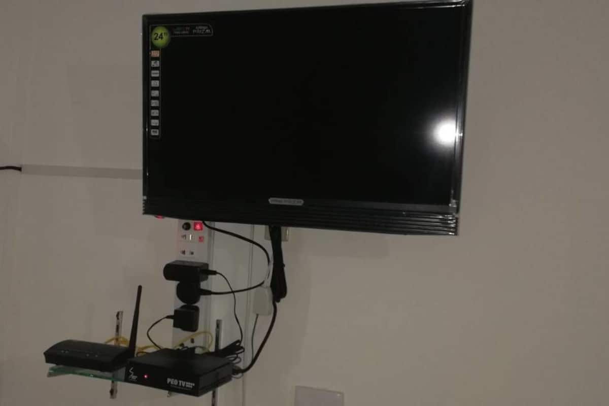 Un téléviseur à écran plat fixé au mur, relié à un lecteur multimédia et à une multiprise.
