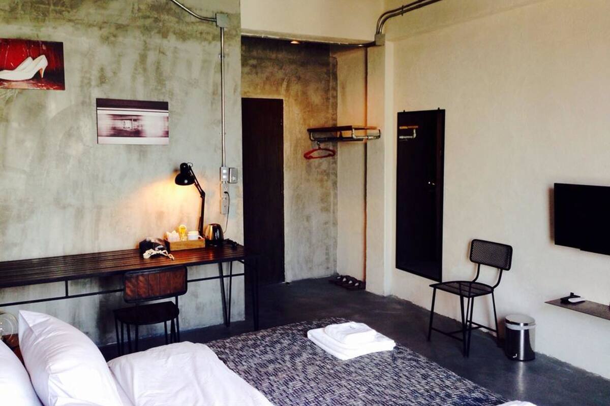 A modern hotel room with a bed, desk, chair, and a TV mounted on the wall.