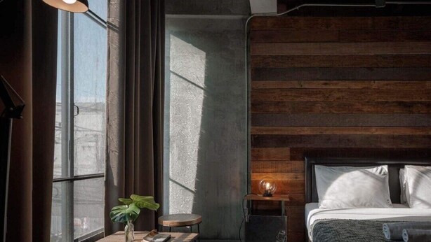 A modern bedroom with a large bed, a small bedside table, a desk with a chair, and a potted plant. - Samantan Hotel at Nimman (Chiang Mai)