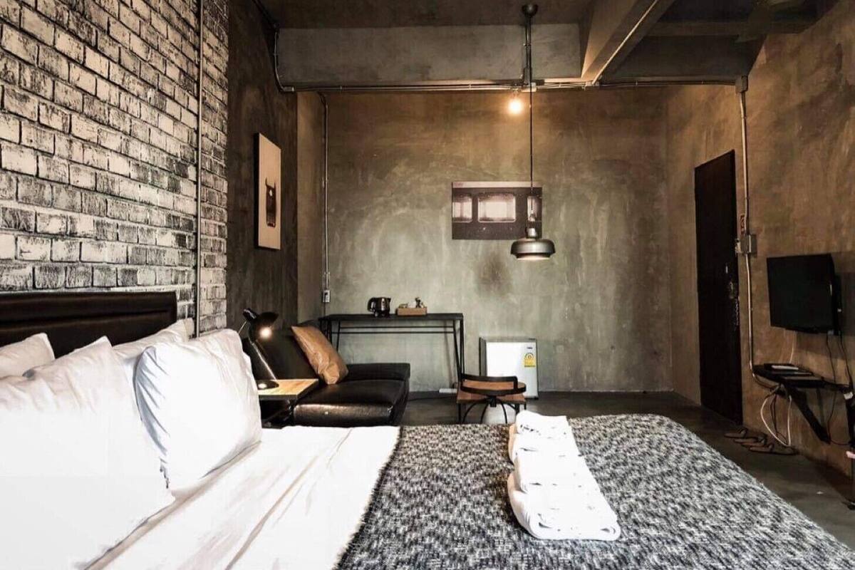 A bedroom with a brick wall, a bed, a desk, and a chair.