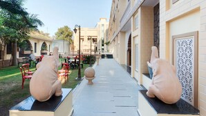 A courtyard with two elephant statues, outdoor seating, and a building with traditional design. - Pushkar City inn (Pushkar)