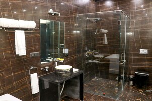 Un baño moderno con ducha envuelta en vidrio, un espejo grande y un tocador negro con lavamanos.