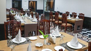 A dining area with multiple tables set for service, wooden chairs, and a patterned floor. - Pushkar City inn (Pushkar)
