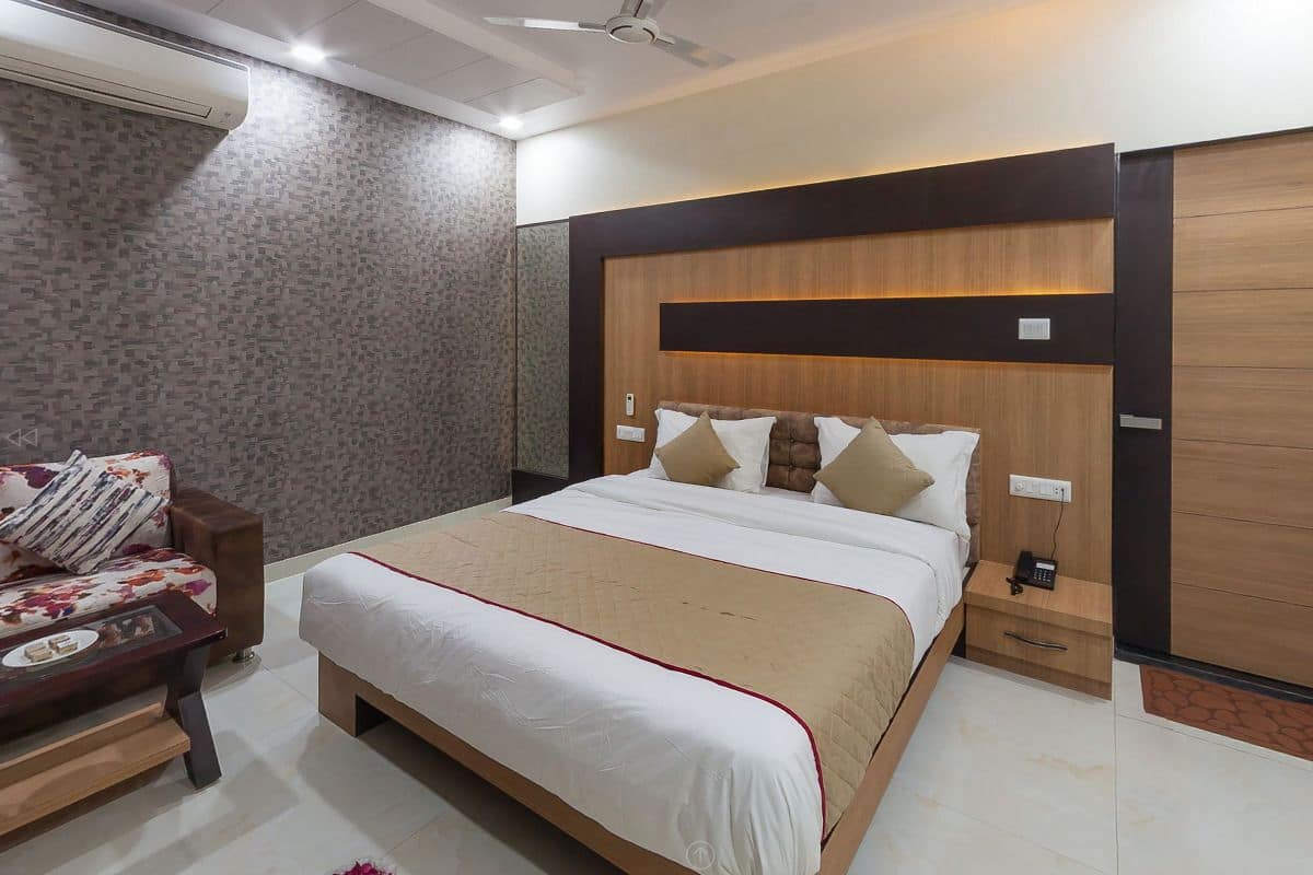 A bedroom with a large bed, a wooden headboard, a bedside table with a phone, and a wardrobe.