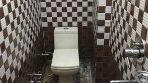 Une petite salle de bain avec des toilettes blanches, des murs carrelés à motifs et un sol en marbre.