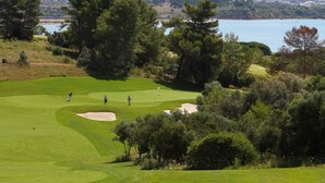 A golf course with sand bunkers, trees, and a view of the sea. - Casa dos Ninos (Silves)
