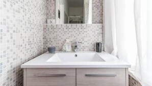 A bathroom with a white sink, a mirror, and tiled walls. - Guest house Roma (Rome)