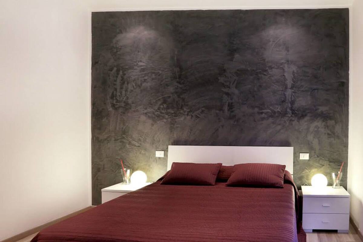 A modern bedroom with a large bed, two bedside tables with lamps, and a textured wall behind the bed.