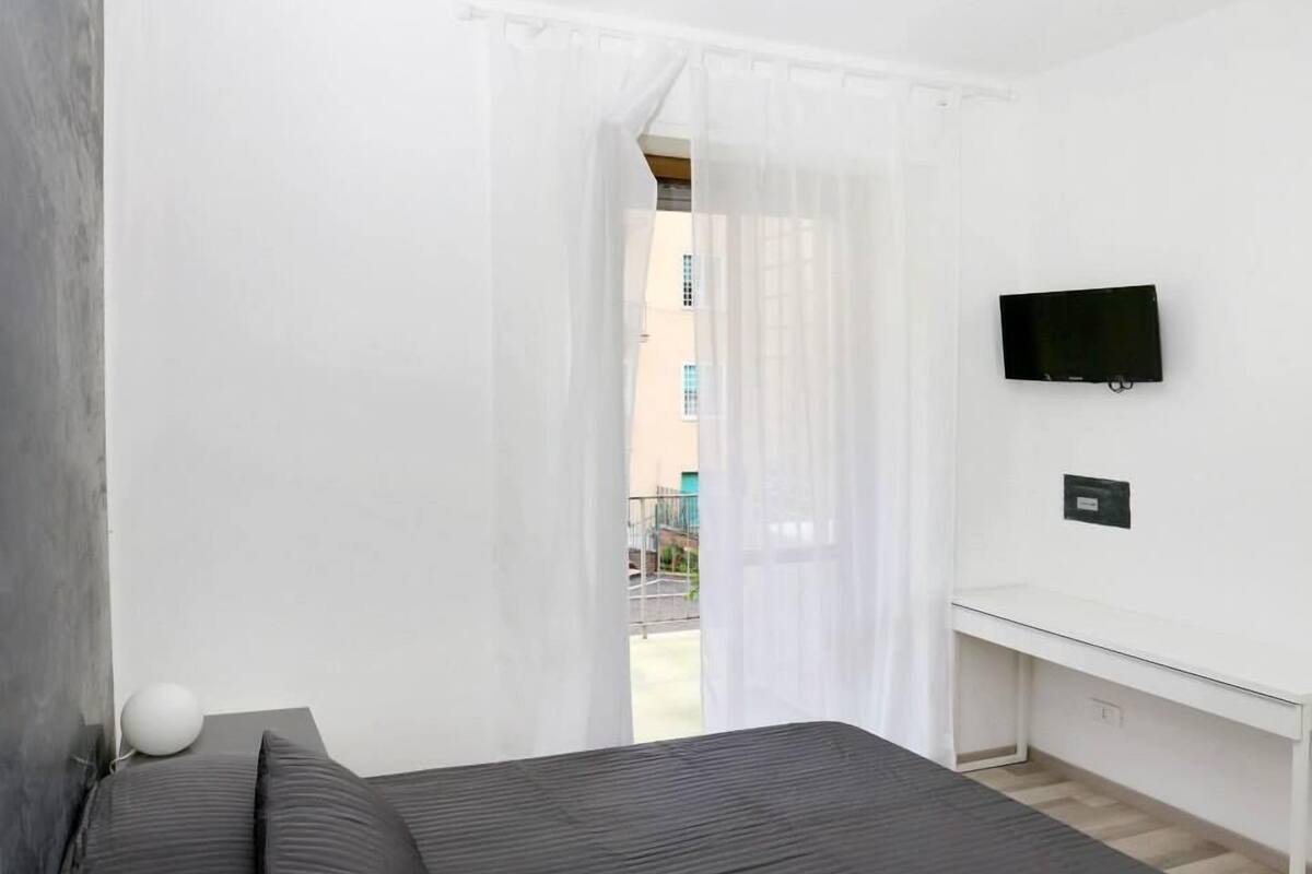 A bedroom with a bed, a desk, and a TV.