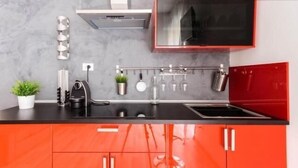 A modern kitchen with a black countertop, red cabinets, and a stainless steel range hood. - Guest house Roma (Rome)