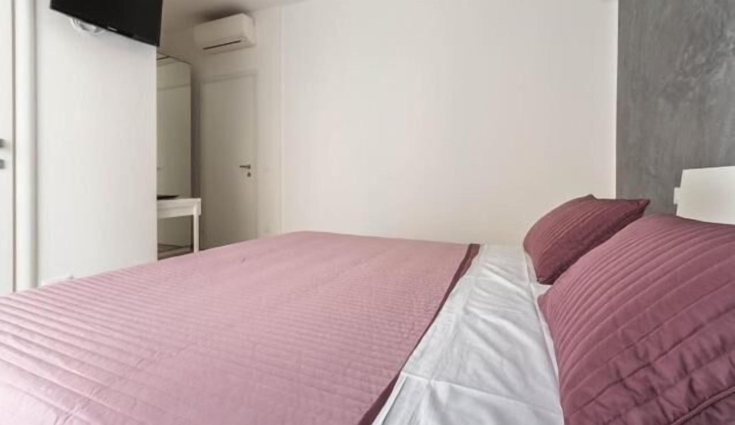 Un dormitorio con una cama, una pared blanca y una pared gris.