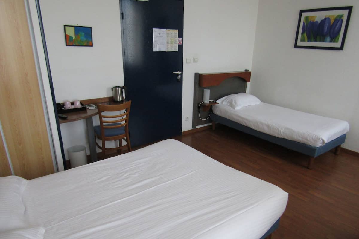 Ein Zimmer mit zwei Betten, einem Schreibtisch, einem Stuhl und einer Tür.