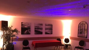A room with a red table, four chairs, a large potted plant, and three paintings on the wall. - Le Creusot Hôtel (Le Creusot)