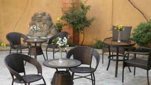 An outdoor patio with wicker furniture and a stone wall.