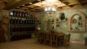 A rustic room with wooden furniture, shelves with bottles, and brick walls.
