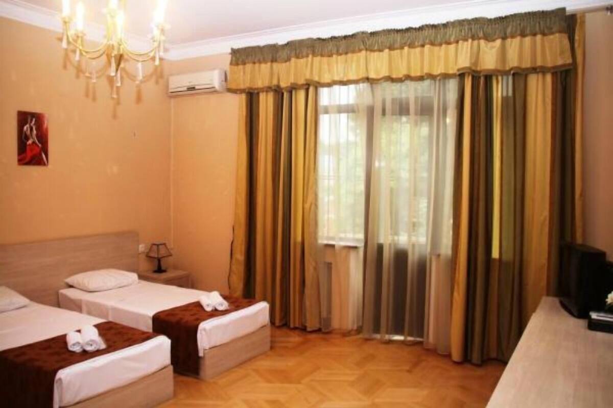 A hotel room with two beds, a chandelier, a television, and a large window with curtains.