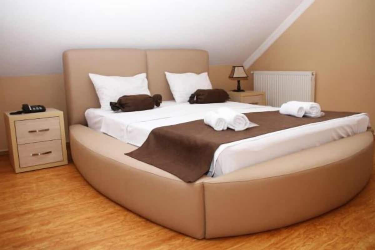 A modern bedroom with a curved bed, a bedside table, and a lamp.
