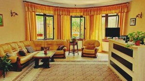 A living room with a sofa set, a coffee table, a side table, and a television.