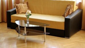 A modern living room with a sofa, a glass coffee table, and a vase with flowers.