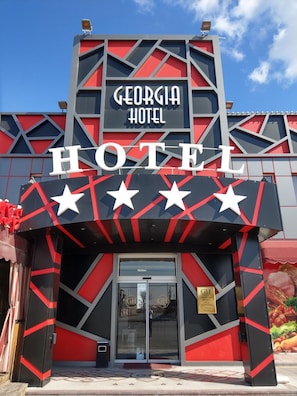 The exterior of the Georgia Hotel with a modern design featuring a large signboard and star decorations. - Georgia Hotel (Kasakh)