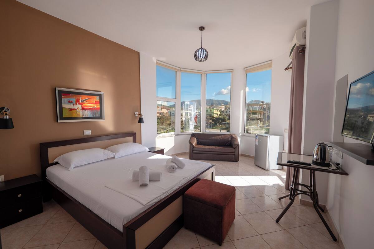 Una habitación de hotel moderna con una cama grande, un sofá, un escritorio y un televisor.