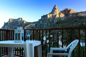A table with a bottle and glass on a balcony overlooking rocky mountains. - Hotel Rural Imada (Alajero)