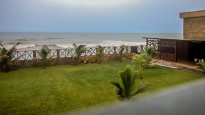 Vista do oceano a partir de uma varanda com área gramada e palmeiras.