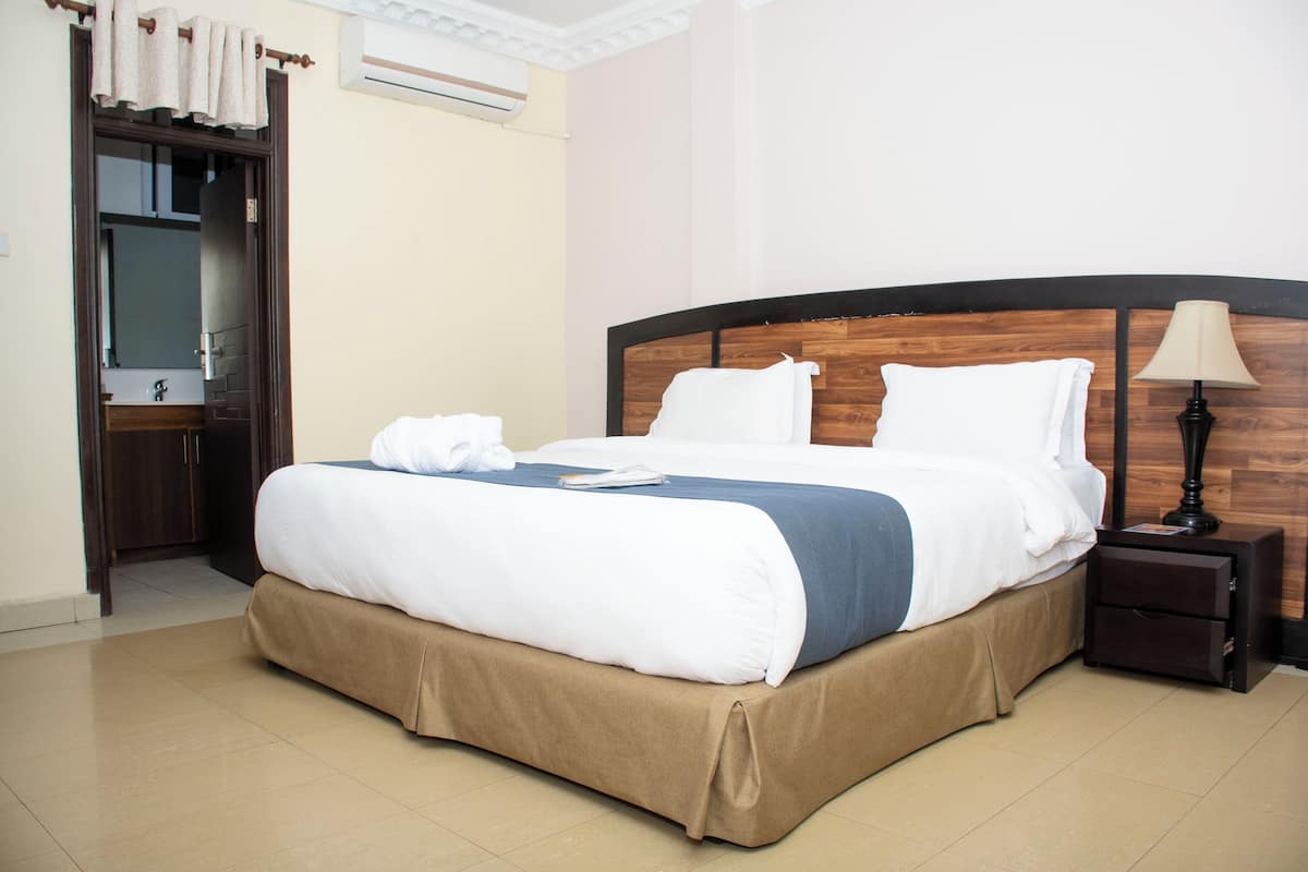 A neatly made bed with a wooden headboard, a bedside lamp, and a nightstand.